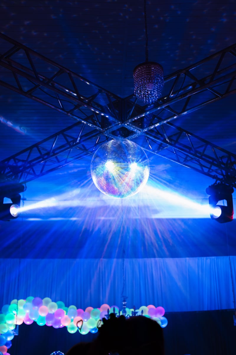 A mirror ball and blue stage lights above a decorated dance venue.